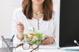 Young woman creative designer eating a salad  in office.