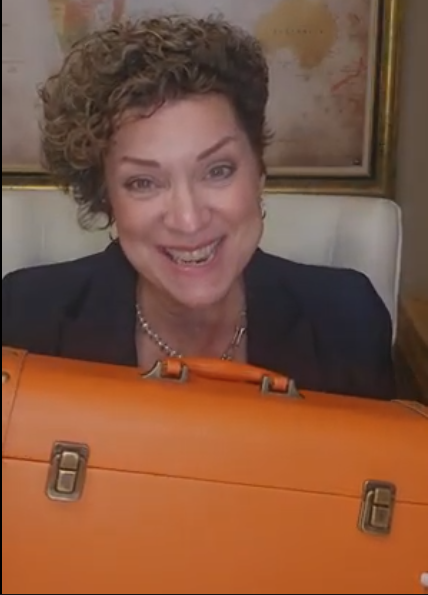 Peggy Vasquez holding her orange "resilience toolkit" suitcase